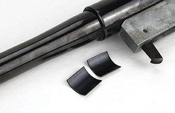 Two thin bedding plates, curved to match the barrel contour, free-float the barrel.